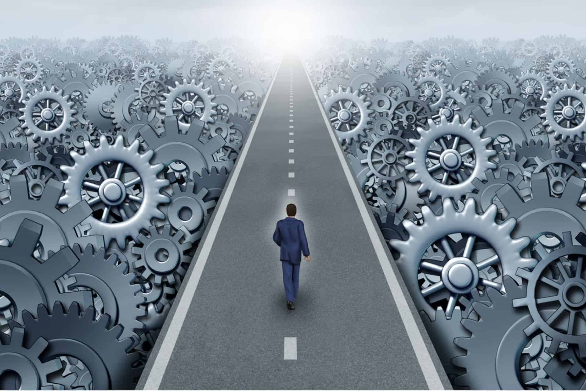 A business person walks down a road toward the horizon surrounded by working gears.
