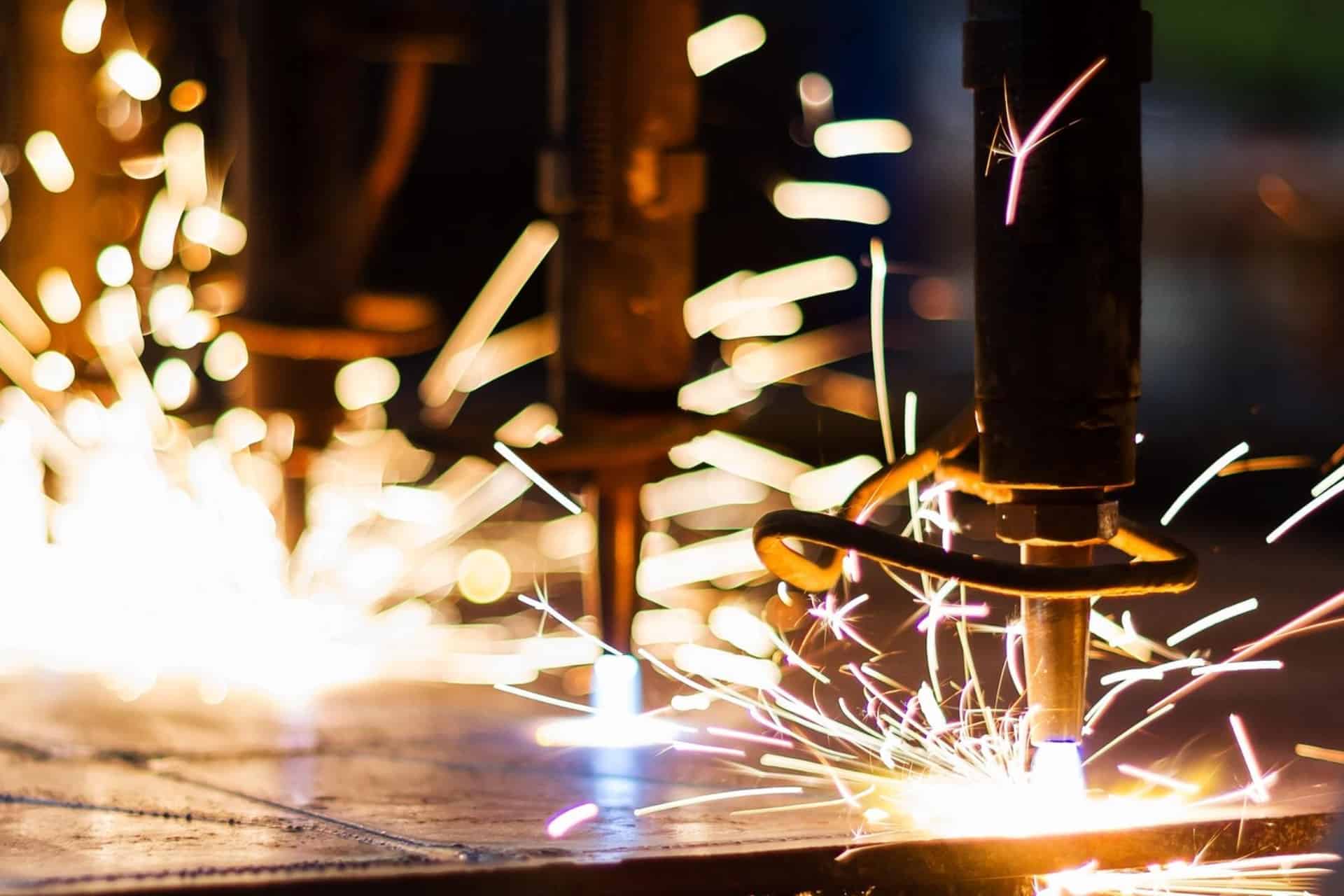 Manufacturing equipment cutting metal with sparks.