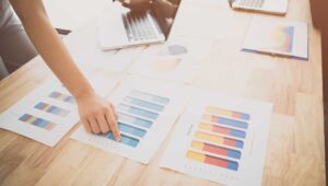 Business woman compares internal audit reports on a wooden desk.