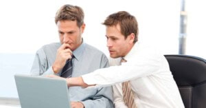Two handsome businessmen working together on a project sitting a