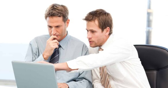 Two handsome businessmen working together on a project sitting a